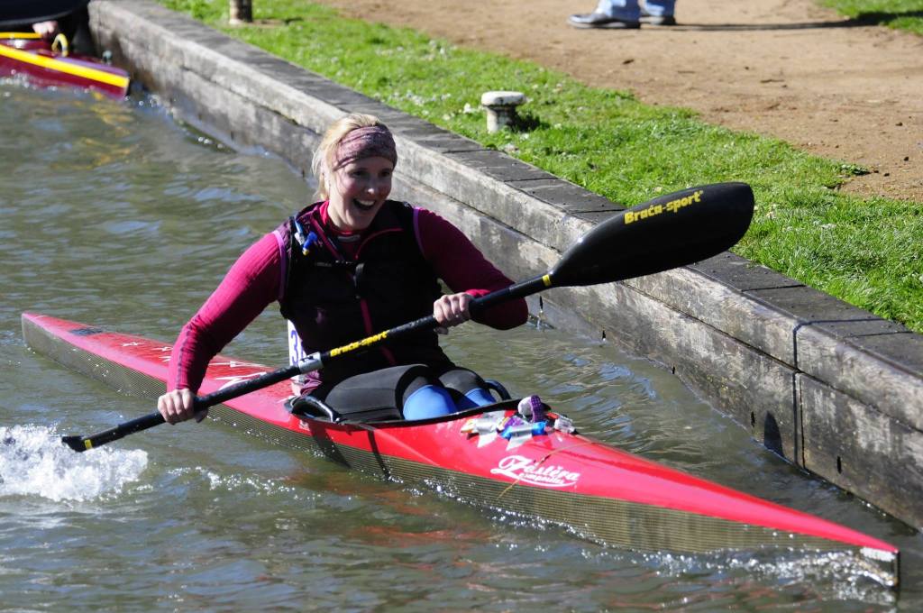 Kat Wilson in K1 pulling into a portage looking like she's having the absolute time of her life. Photo courtesy of Fred Taylor on Facebook.